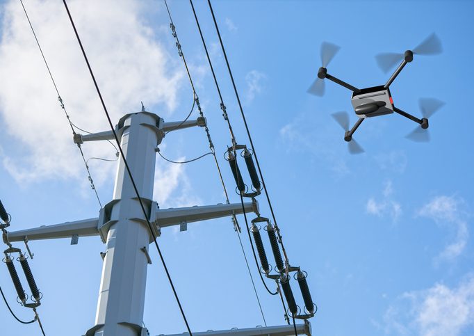 drone inspecting electricity power lines Electric wires on poles with drone hovering above them.