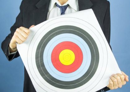 Man in suit holding a target in front of himself.