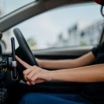 Gig driver with mask looking at her phone.