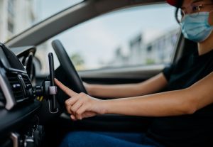 Gig driver with mask looking at her phone.