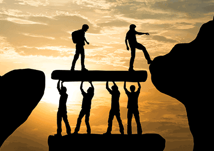 Risk work ambition care entrepreneur support With dramatic sky background, slhouette figures crossing a precipice.