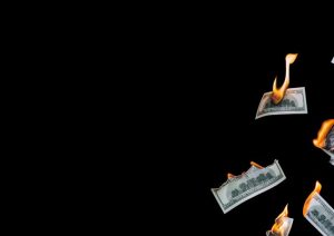 Burning $100 bills floating in blackness.