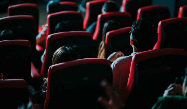 rear-view-group-of-audience-watching-movie-in-cinema-picture-id1334590638