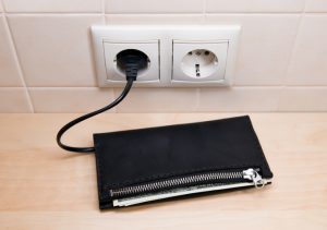A wallet that appears to be connected by a cord to a wall socket.