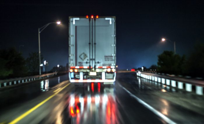 Rear view of a semi at night on a wet highway.