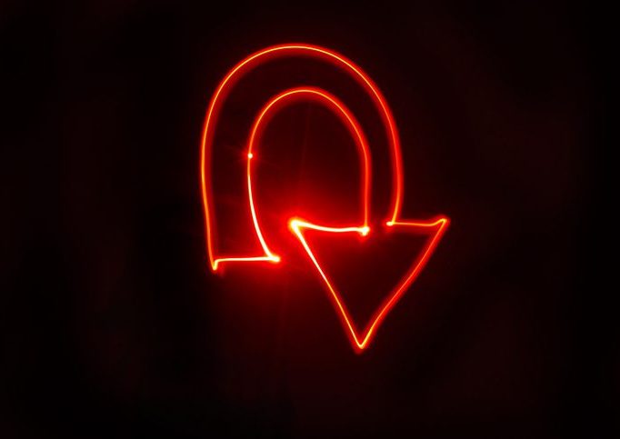 U turn arrow bright red light painting Red arrow on a black background turning in on itself.