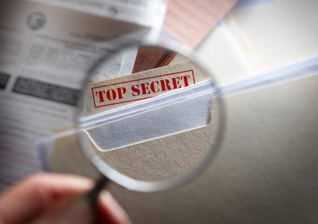 someone-looking-at-top-secret-files-with-magnifying-glass-picture-id185124853