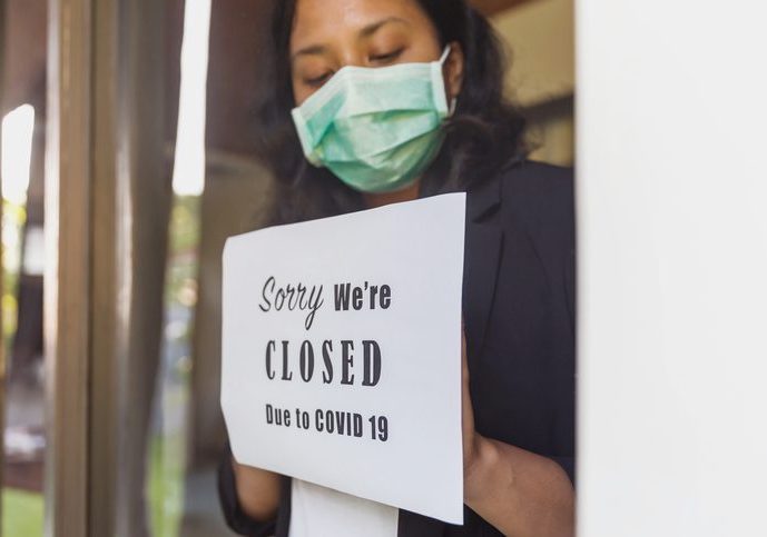 Portrait shot of business owner putting a closing down poster into a window during Covid 19 outbreak