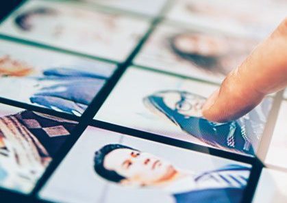 choice experts select web An index finger pointing to a page that has head shots of numerous people on it.