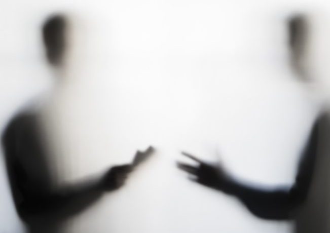Two men negotiating behind curtain Two symmetical shadowy male figures, out of focus, facing each other and gesturing as if talking to each other.