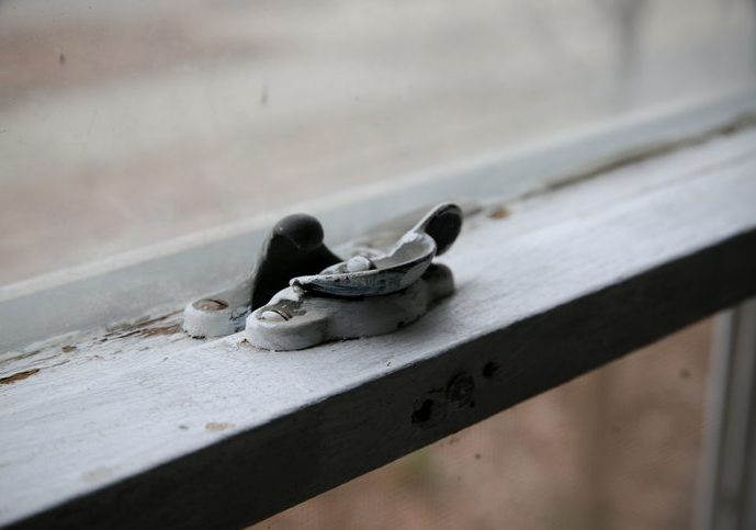 Old Wood Window Latch Peeling Lead Paint Close-up of a household window, showing the latch, and with old flaking paint.