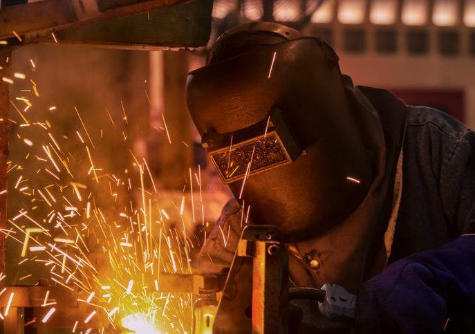 Industrial worker is welding in automotive part factory Welder at work, sparks flying.
