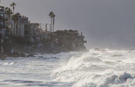 Storm Surge A rocky sea coast with rising sea waves crashing against it.