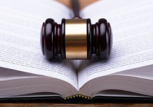 Open law book with a judge's gavel at the center where the pages meet.