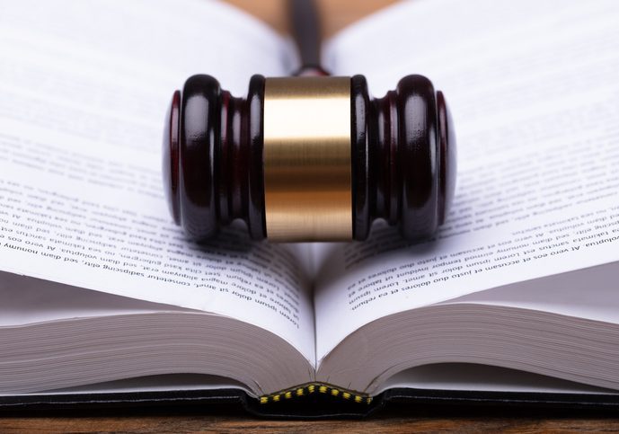 Close-up Of Gavel And Law Book Open law book with a judge's gavel at the center where the pages meet.