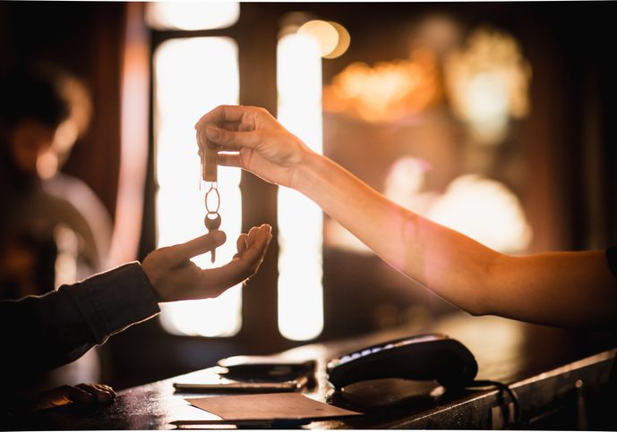 Hotel Receptionist giving the Room Keys Somebody's arm over a desk dropping a key into the hand of another arm over the desk.