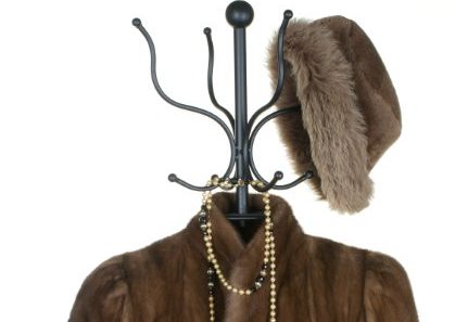 000018726761 FUR COAT RACK ABSENCE Absent MISSING GONE WAITING 420 Fur coat, gold necklace and fancy possibly men's fur hat, hanging on a coat rack.