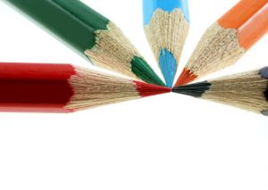 Four sharp colored pencils converging on a single point.
