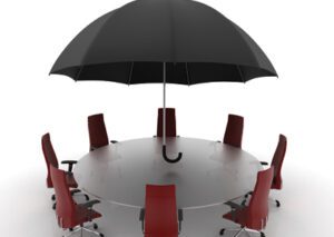 Umbrella over a circular conference table, around which are spaced empty office chairs.