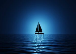 A lone silhouette sailboat on a calm blue sea.