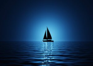A lone silhouette sailboat on a calm blue sea.