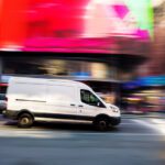 Delivery van in a city, with a blurred background suggesting it might be speeding.