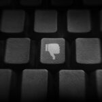 Keyboard in shadows, with a white "thumbs down" image on one of the keys.
